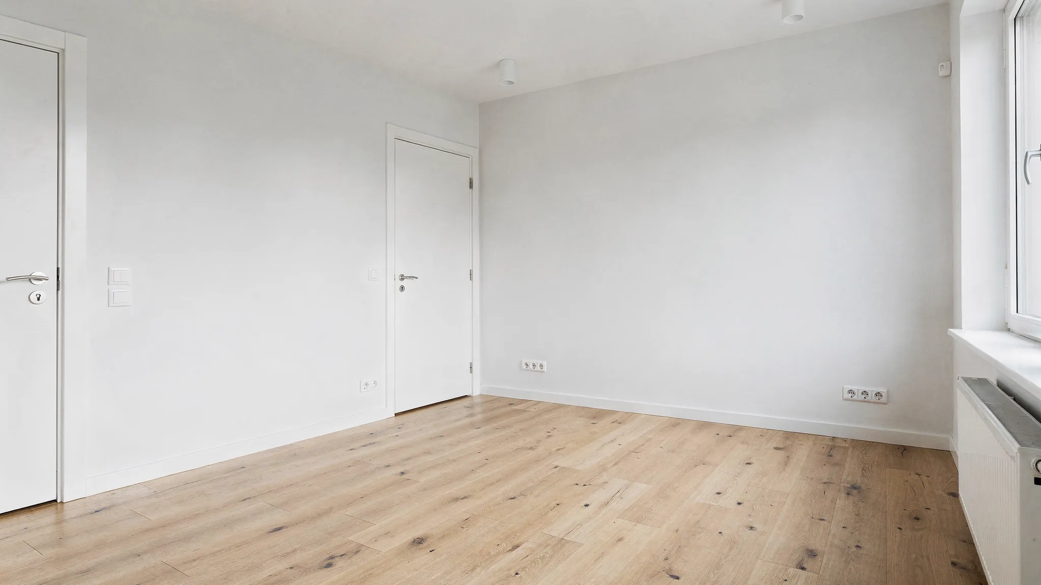 Nymalet lys lejlighed med glatte hvide vægge, pæne lofter, rene fodlister og et enkelt moderne udtryk, klar til indflytning eller fremvisning.