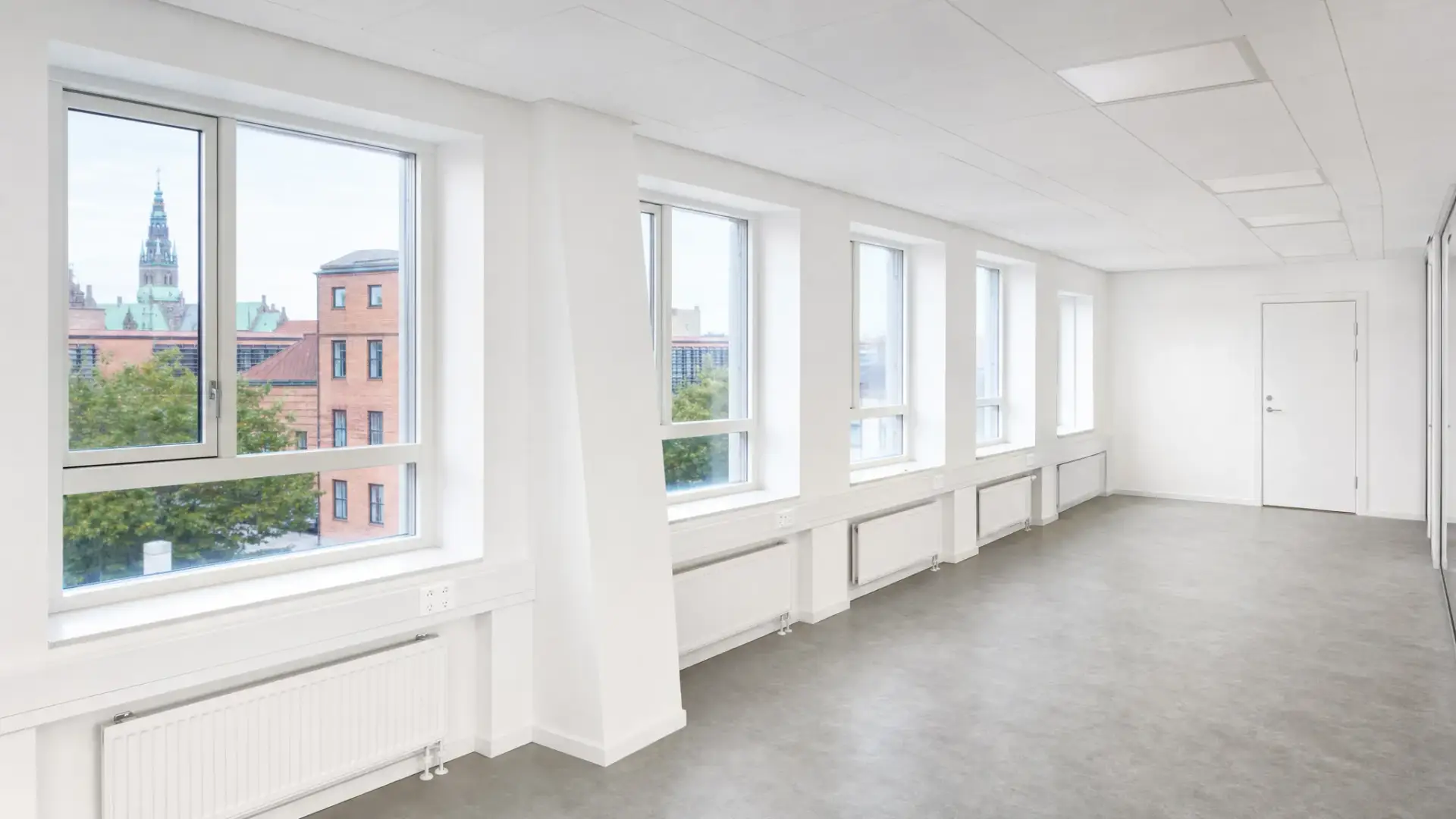 Nymalede lyse vægge og lofter i et ryddeligt kontor i Hillerød, med skarpe kanter ved vinduespartier, hvide paneler og afdækket gulv klar til brug.